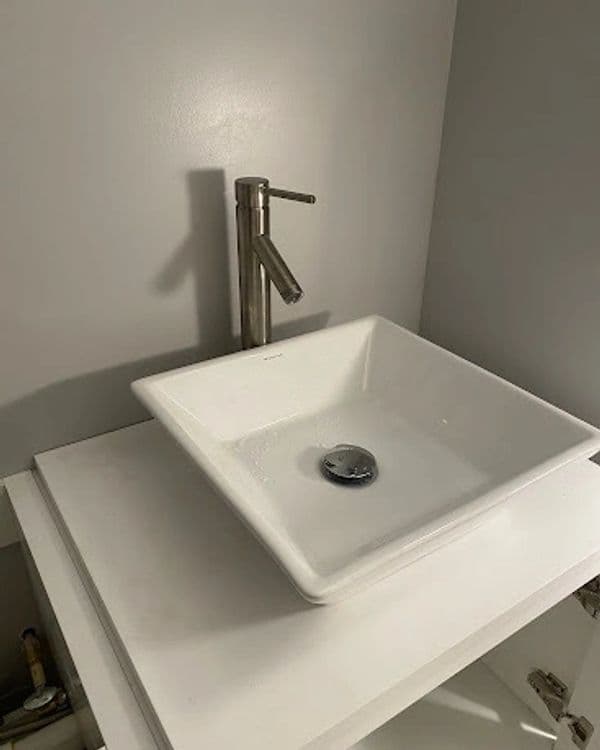 Modern square bathroom sink with polished faucet on a minimalist countertop.