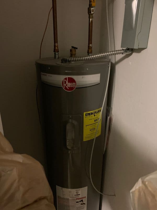Rheem water heater in a closet with energy guide label and copper piping.