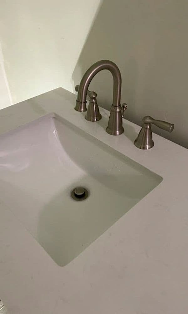 Modern bathroom sink with brushed nickel faucet on a white countertop.