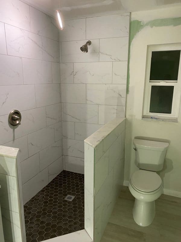 Renovated bathroom featuring a walk-in shower, modern tiles, and a toilet.