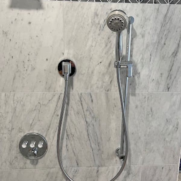 Modern marble shower wall with chrome showerhead and controls.