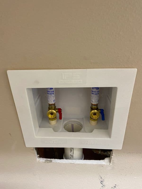 IP Supply water manifold with hot and cold shut-off valves installed on a wall.