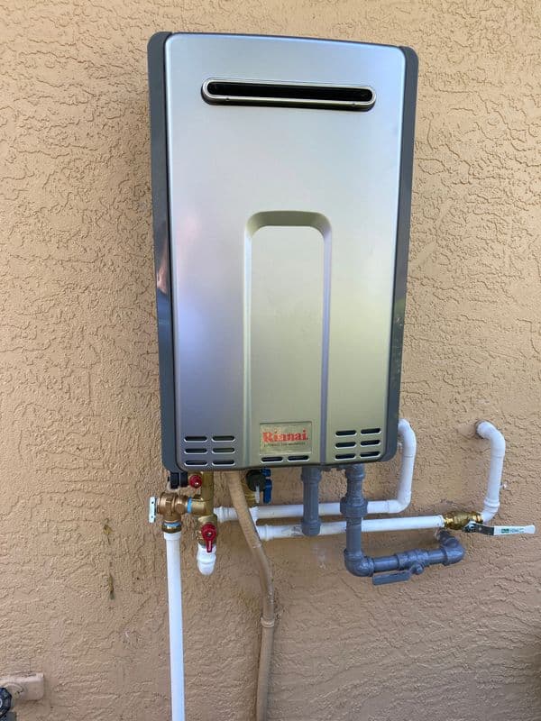 Tankless water heater mounted on wall with plumbing connections. Efficient home heating solution.
