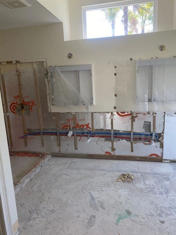 Renovation in progress: exposed wall with plumbing and construction materials in a room.