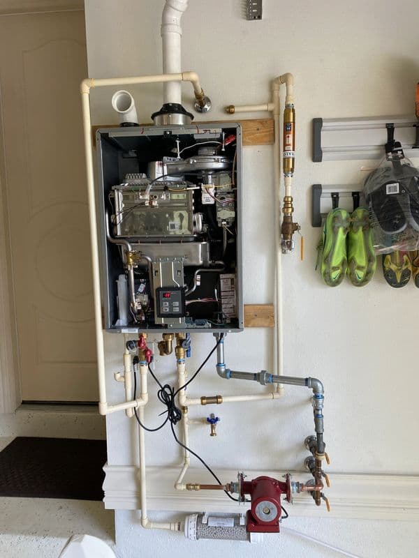 Gas boiler installation with pipes and fittings in a garage setting.