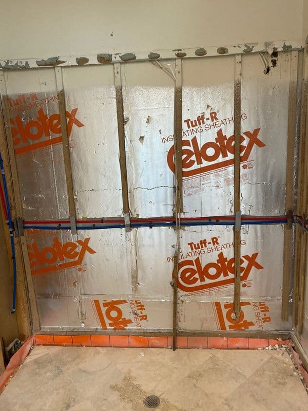 Insulated wall with reflective sheeting and plumbing for a bathroom renovation project.