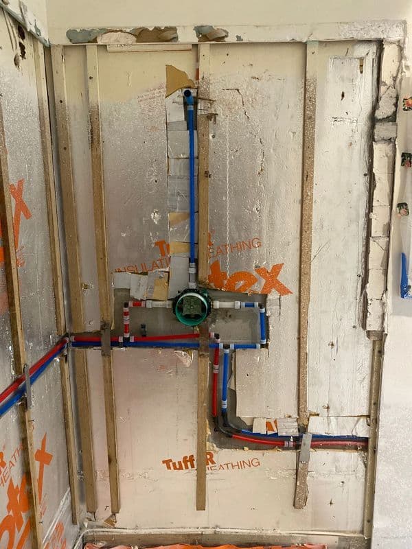 Plumbing installation with blue and red pipes on insulated wall, showing fixtures and connections.
