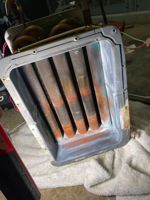 Copper coils inside an air conditioning unit, showing rust and corrosion details.