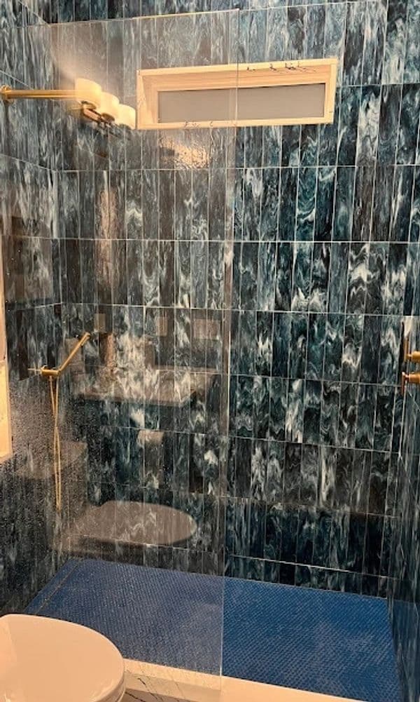 Modern bathroom with blue marble tiles, walk-in shower, and gold fixtures.