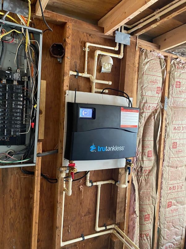 Trutankless water heater installation with visible plumbing and electrical connections.