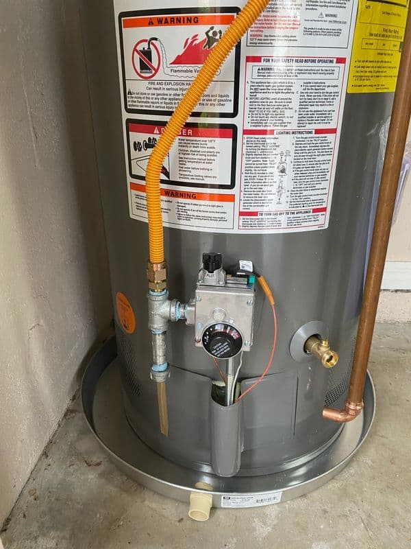 Water heater installation with safety warnings and gas connections visible.