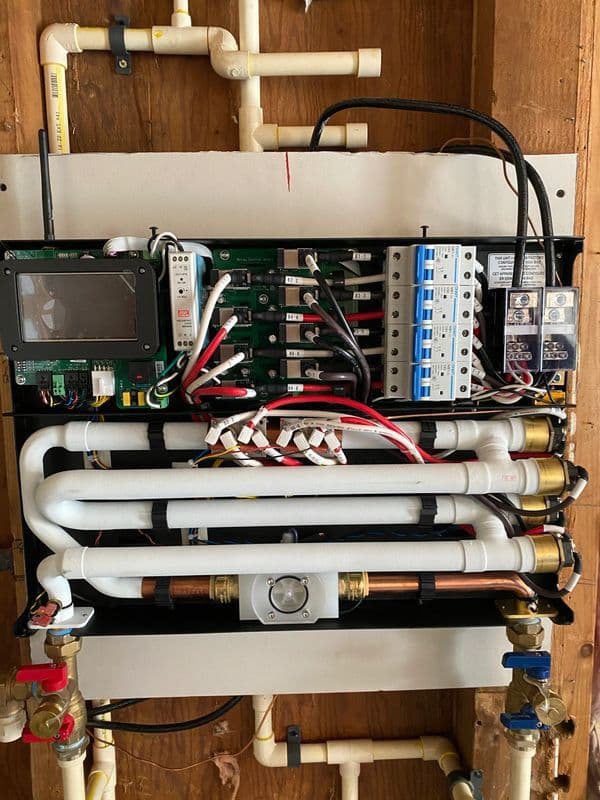 Complex plumbing control panel with pipes, circuit boards, and electrical components.