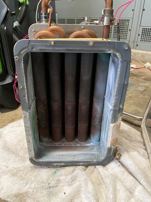 Cross-section of a cooling coil with copper tubes, showing rust and wear details.