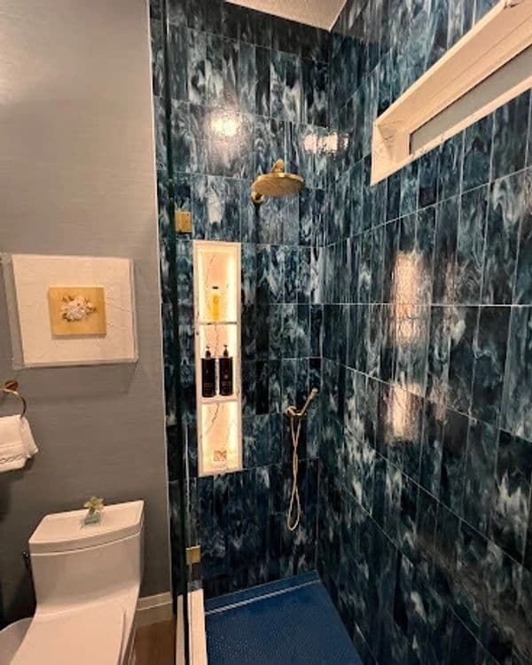 Modern bathroom with blue marble tiles, glass shower enclosure, and a stylish showerhead.