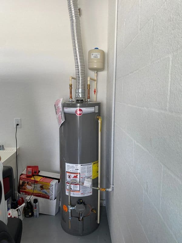 Gray water heater installed in garage with vent and plumbing connections. Safe and efficient.