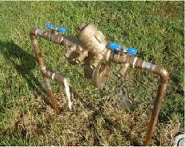Brass water valve and piping system on grass foundation for irrigation control.