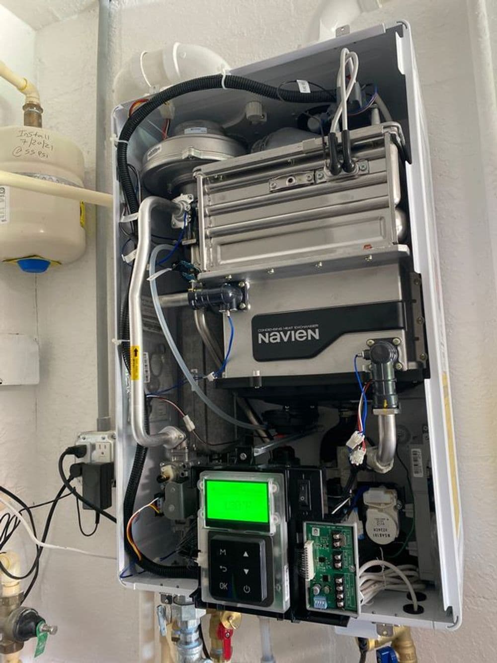 Navien tankless water heater with digital display and visible plumbing connections.